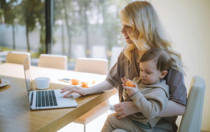 A working woman holding a baby with laptop