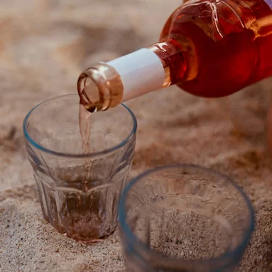 glasses in the sand and a bottle of alcohol