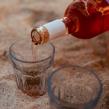 glasses in the sand and a bottle of alcohol